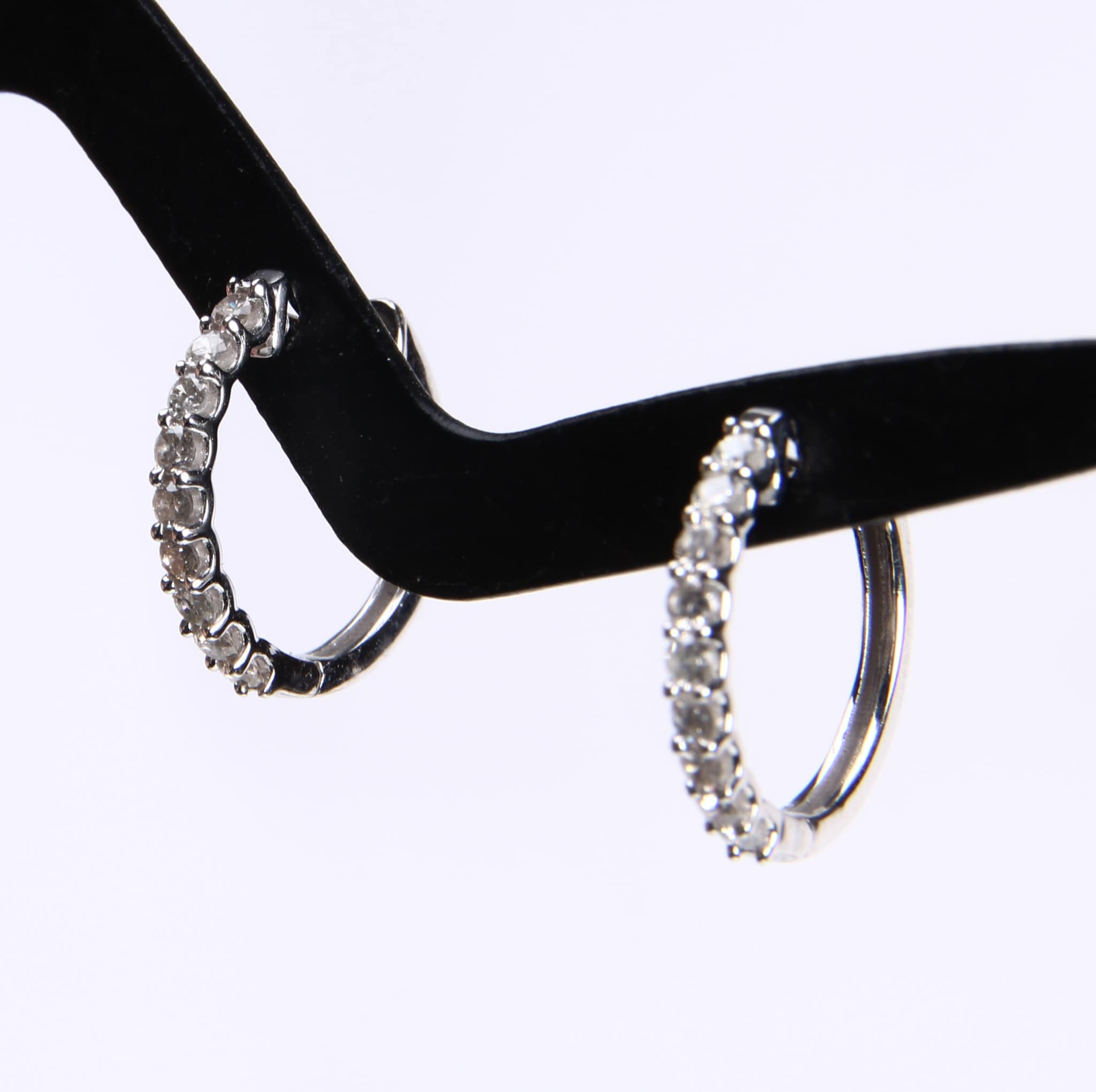 A pair of huggies diamond earrings in 14 kt. white gold, totaling 0.25 ct. (2)