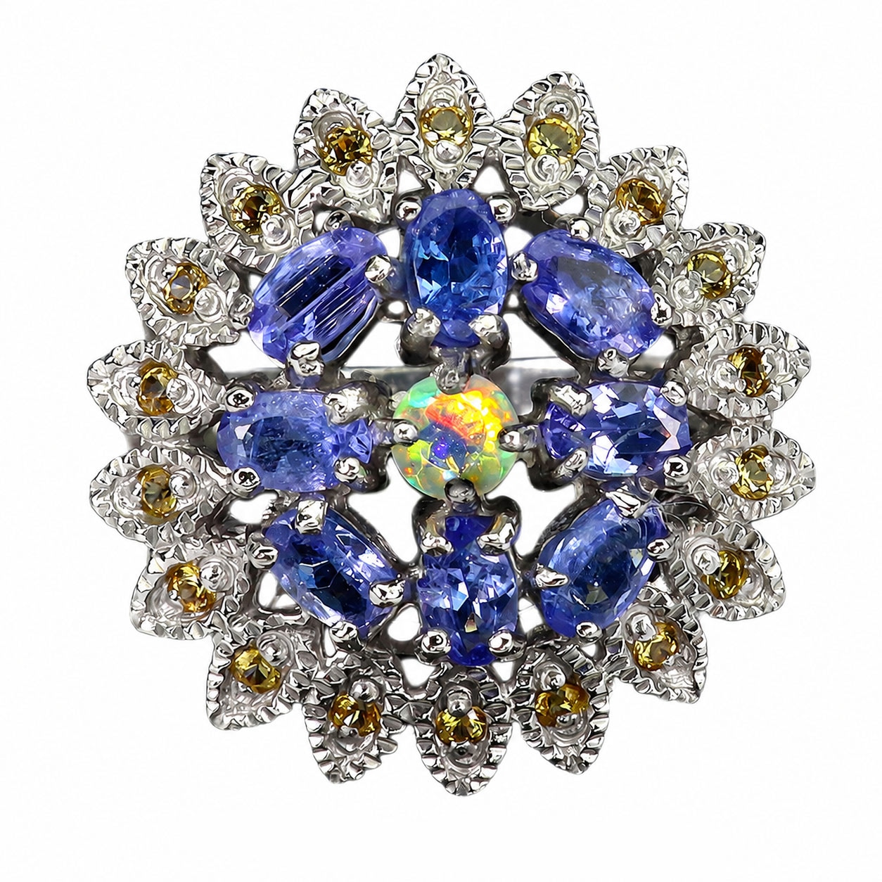 Ring in rhodium-plated sterling silver with a faceted round opal surrounded by numerous tanzanites and yellow sapphires. Ring size 57