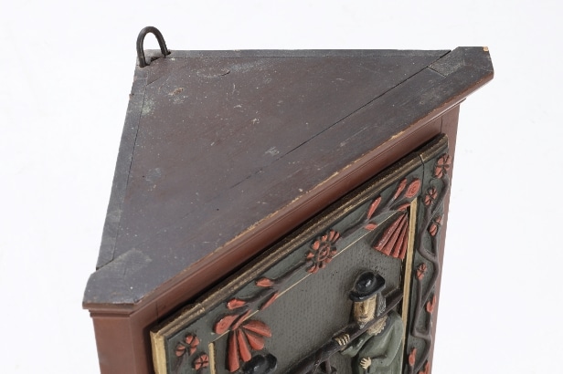 Small corner cabinet with carved figures on the door