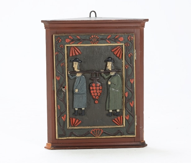 Small corner cabinet with carved figures on the door